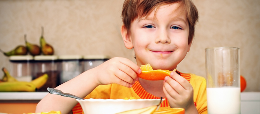 menino jovem sorrindo e segurando um pedaço de fruta