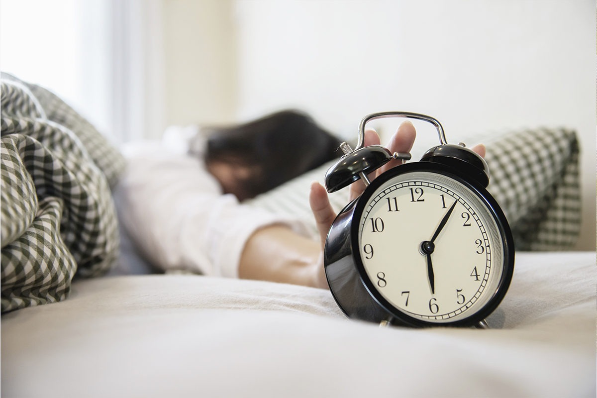 mulher sonolenta segurando um alarme de manha